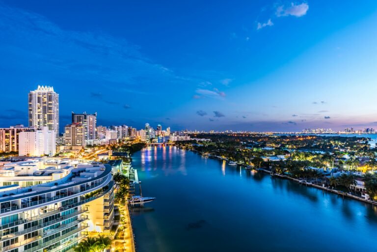 Stunning aerial view of Miami's illuminated waterfront skyline during dusk showcasing modern architecture and vibrant city lights.